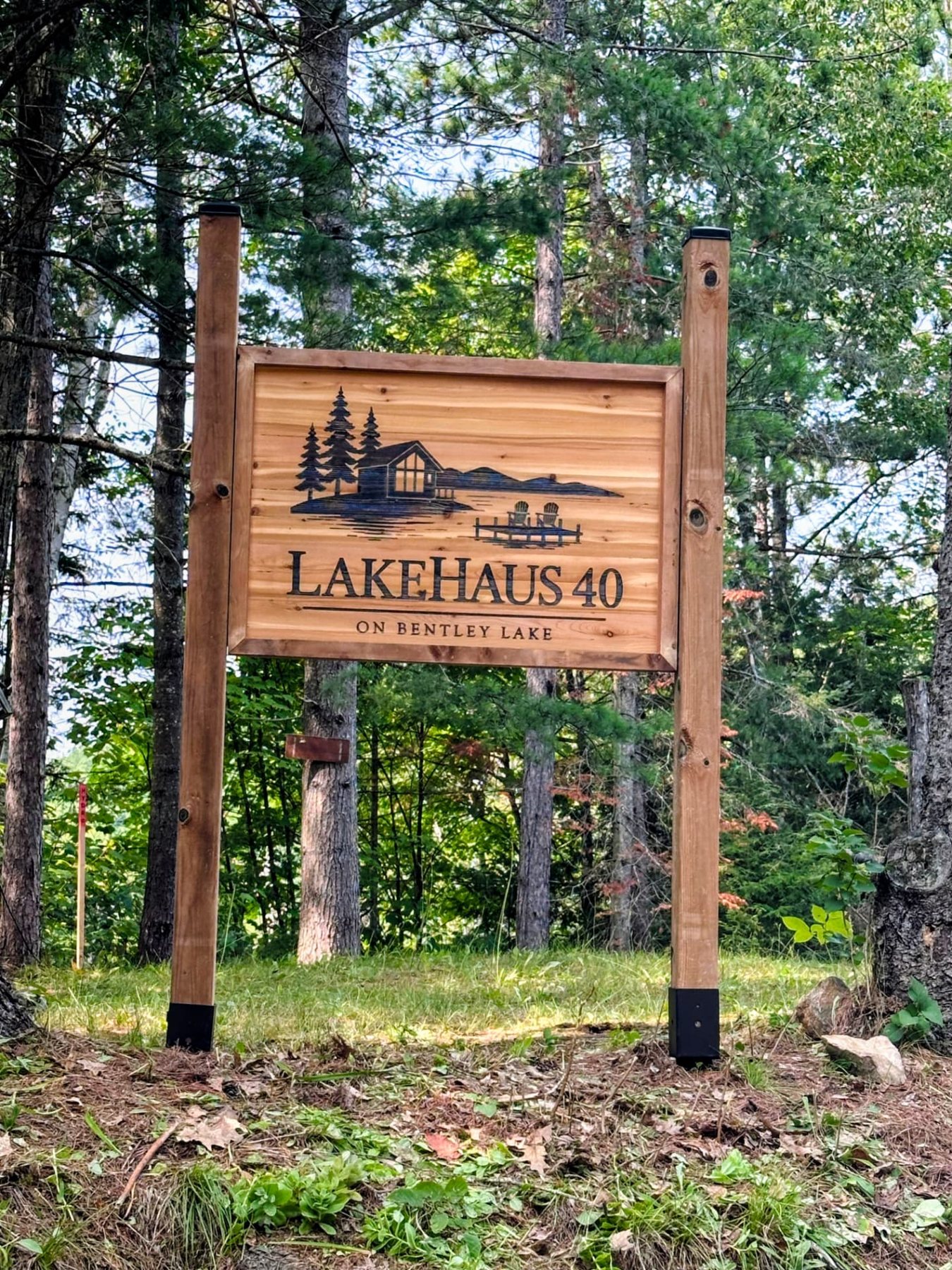 LakeHaus 40 cedar cottage sign mounted on posts in the woods